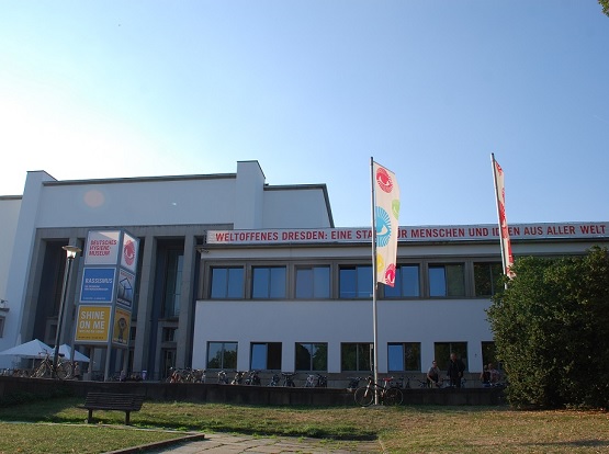 Man sieht die Vorderansicht des Deutschen Hygiene Museums. Es gibt zwei Fahnenmaste. Vor dem Gebäude stehen viele Fahrräder.