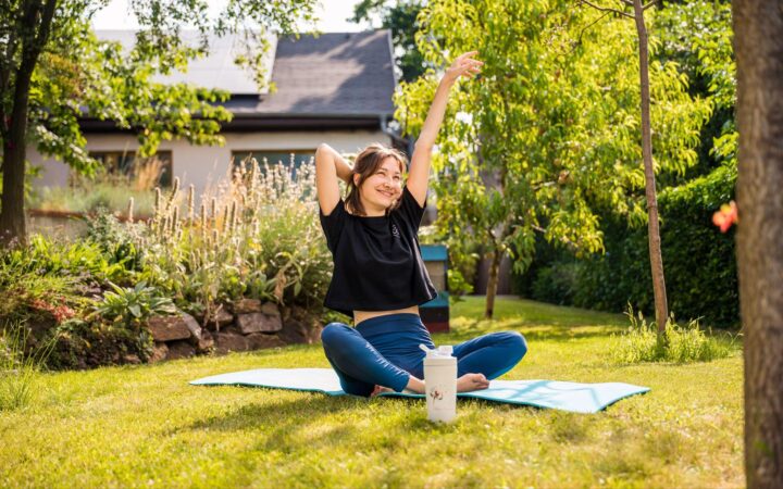 Frau beim Yoga im Garten mit personalisierter Ink2Heart-Thermoflasche